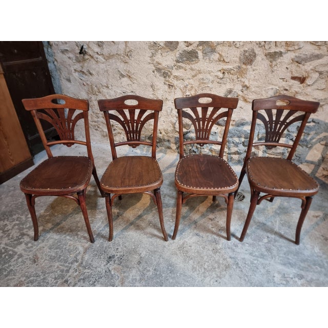Set of four antique French bistro chairs by Thonet, dating from circa 1920. Crafted from beech wood, the chairs feature...