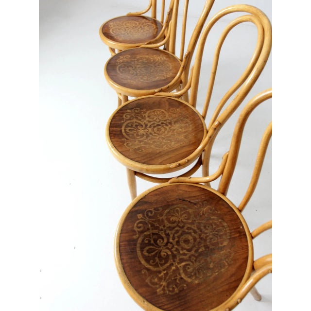 This is a set of four antique Thonet bentwood chairs in a classic Art Nouveau café style. Each chair features an elegant...