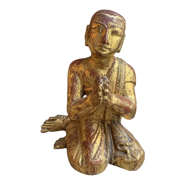 A lacquered and gilded Buddhist monk in a traditional pose with hands together and a serene facial expression. Gilt over...