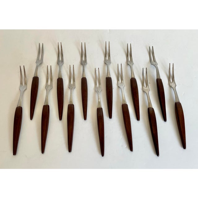 This vintage set of mid-century appetizer forks dates to approximately the 1950s-60s and features sleek stainless steel...