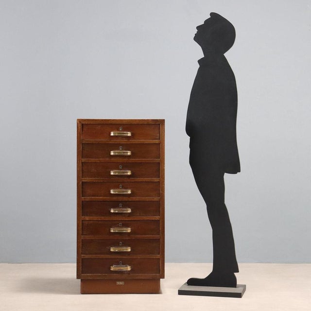 8-drawer chest of drawers in stained poplar veneer and brass handles. This piece is attributed to the mentioned...