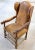 Antique aged and distressed leather and carved wood winged armchair with bronze accent tacks. In the William and Mary...