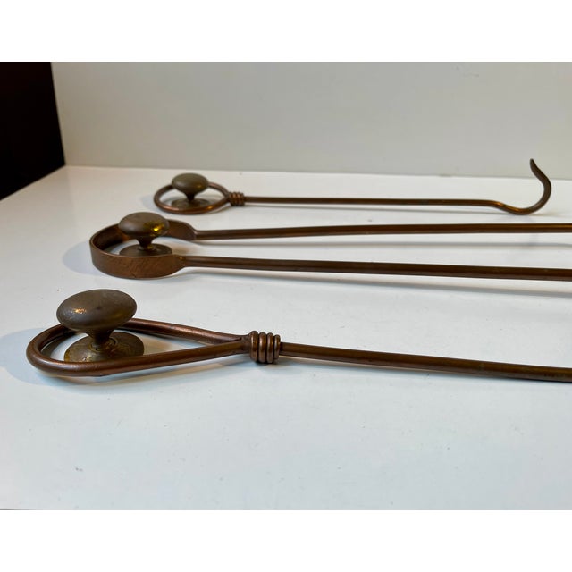 A wall mounted 1960s fireplace tool set executed in partially twisted copper. The set comes with 3 patinated solid brass...