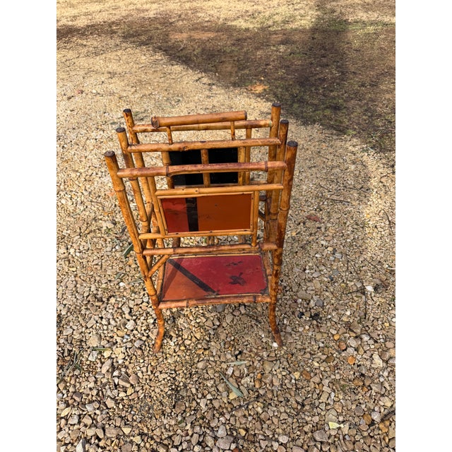A beautiful antique English bamboo and lacquer tiered magazine rack with lower shelf, circa 1880. This magazine rack is...