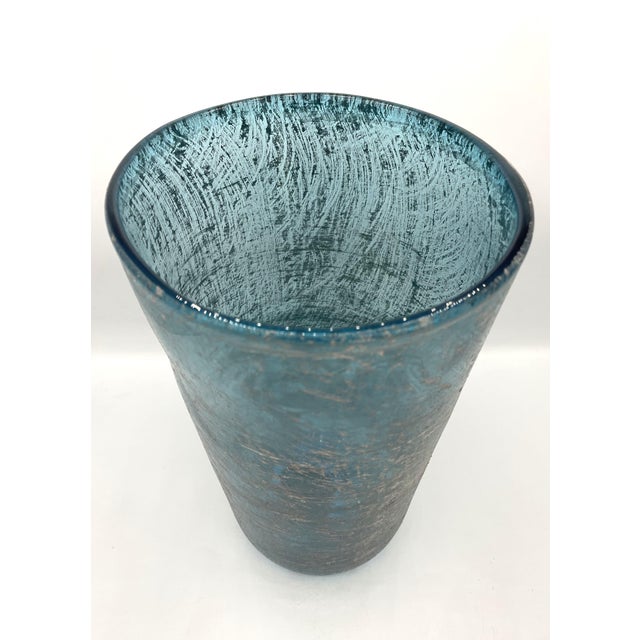 Oval-shaped vase in aquamarine glass with an all-over metallic decoration. The designer is Toni Zuccheri, who began...