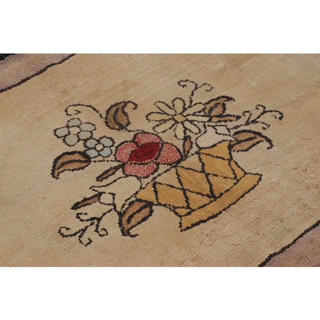 This antique 3x5 hooked rug, circa 1920–1929, features a charming floral basket medallion framed by stylized corner motifs...
