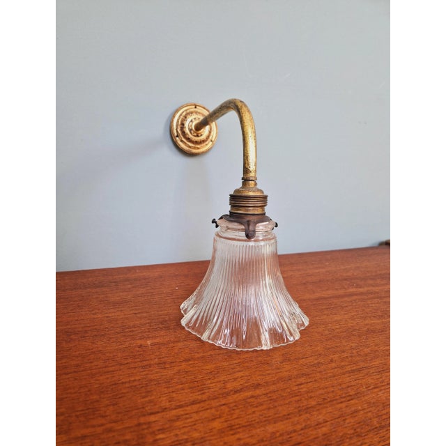 A bronze wall light with a grooved transparent glass bobèche, early 20th century. Dimensions: 13 x 28 x 27 cm Up to 250V...