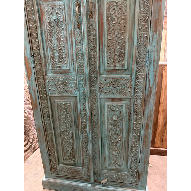 Infuse your space with timeless elegance using this antique blue hand-carved armoire, a beautifully detailed cabinet that...