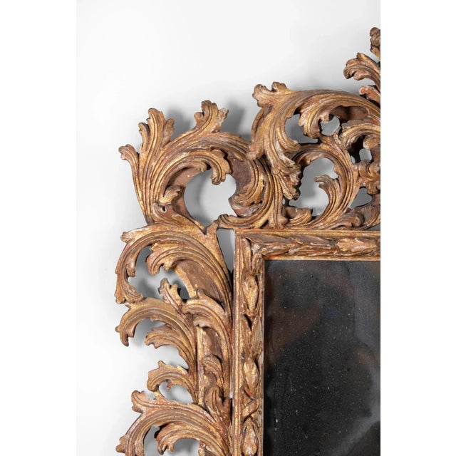 A mid-19th century French Baroque style carved giltwood mirror featuring an intricate laurel leaf design surrounding the...