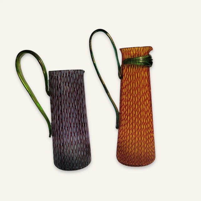 This pair of murano glass pitchers was designed by Romeo Gigli b. 1949, an Italian designer of fashions and perfumes, and...