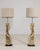 Pair of carved giltwood floor lamps in Antique Gold. The antique gold surface highlights ornate scrolled columns, linen...