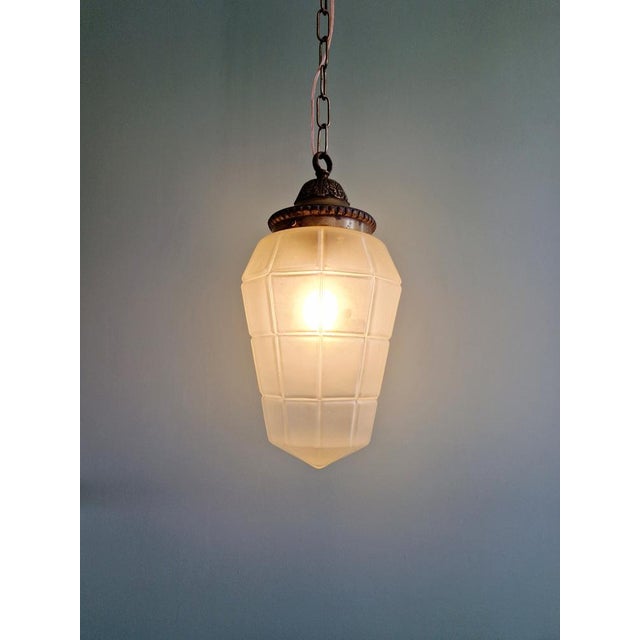 Art Deco pendant light in faceted satin glass with a bronze and brass mount, 1920s-30s. The suspension has been re-...