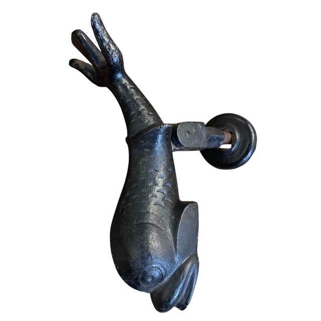 Crafted from heavy cast iron, this vintage architectural door knocker features a detailed design of a stylized sea...