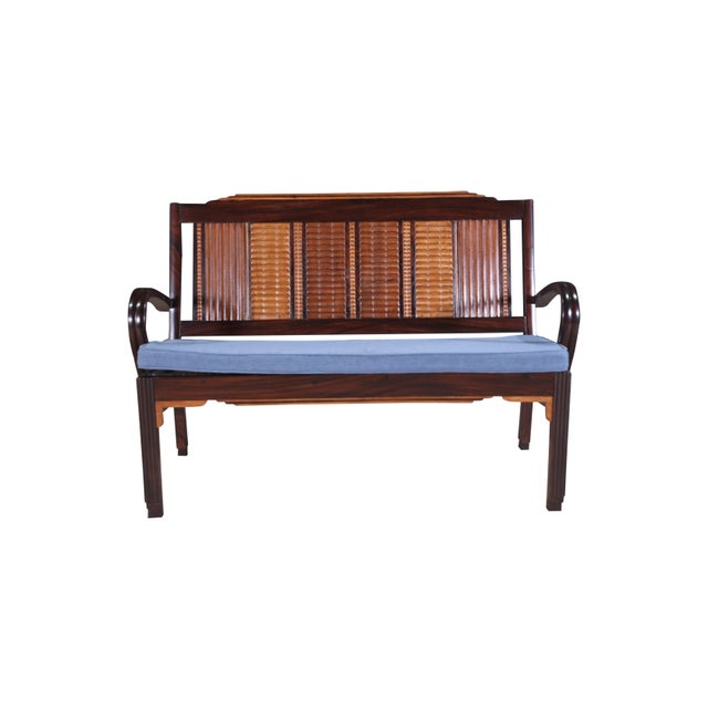 A Mid-Century Modern Loveseat featuring carved teak, satinwood and rosewood with caned seats. Caning is redone in a...