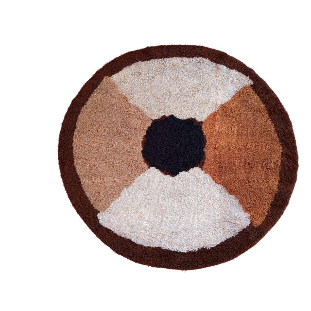 This rug features a geometric design in warm colors. It's divided into four sections that meet in a black center. Each...