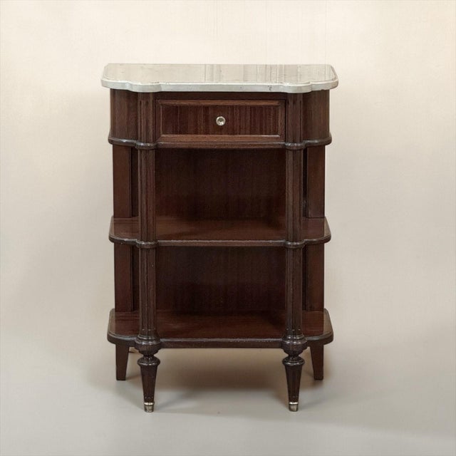 Petite Louis XVI Marble-Top Console in Mahogany is as refined as it is diminutive, crafted in rich mahogany and crowned...