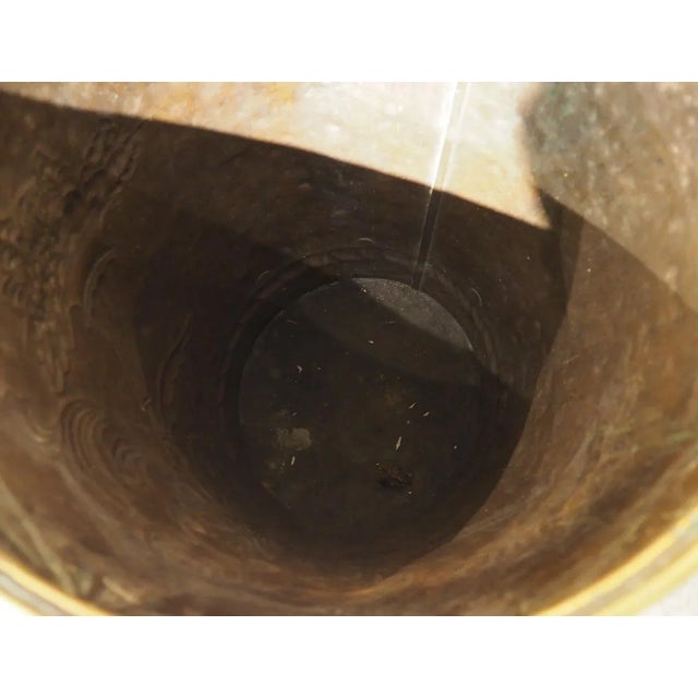 Hammered from the verso side, in a metalworking technique known as repousse, this polished brass wine harvest hotte has...