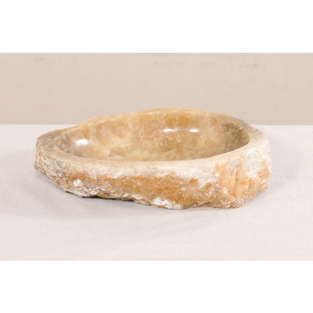 A single natural onyx sink basin with original live edge. This carved vessel sink, created from a rough onyx rock, has a...