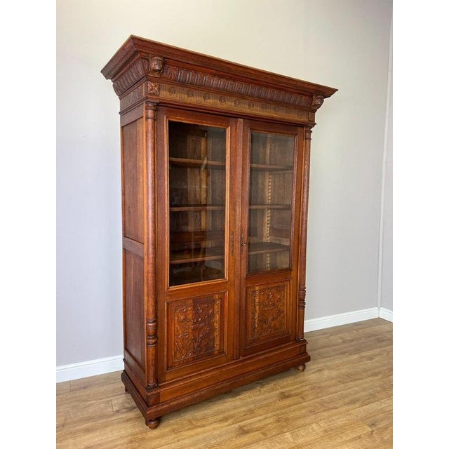 A striking Antique French bookcase in Oak, featuring an imposing architectural form with two tall glazed doors, richly...