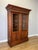 A striking Antique French bookcase in Oak, featuring an imposing architectural form with two tall glazed doors, richly...