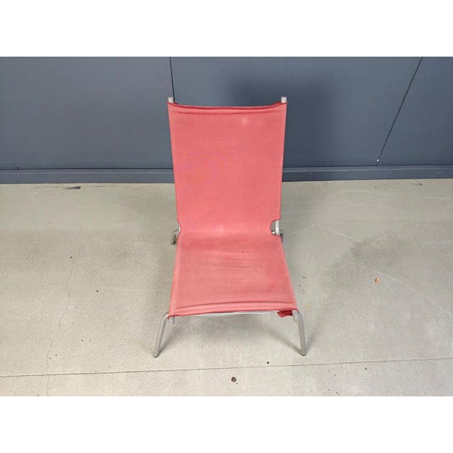 Late 1990s lounge chair designed by Fabiaan Van Severen consisting of a grey tubular metal crossed legged frame with a red...