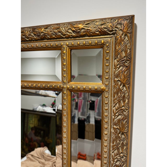 Giltwood-framed mirror by The Bombay Company, featuring an ornate floral border complemented by a decorative geometric...