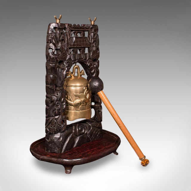 This is an antique tea ceremony gong. An Oriental, carved mahogany stand with brass bell, dating to the Edwardian period,...