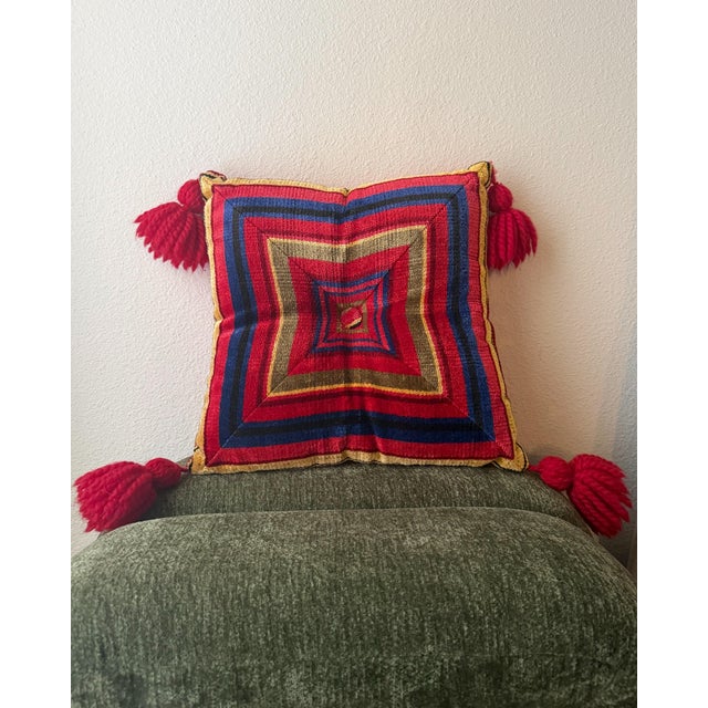 A vivid vintage accent pillow featuring a textured handwoven geometric face in saturated red, navy blue, mustard gold, and...