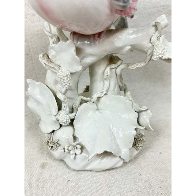 Vintage pair of ceramic bird figurines hand painted with pink and gray accents on a white glaze shown perched on a branch...