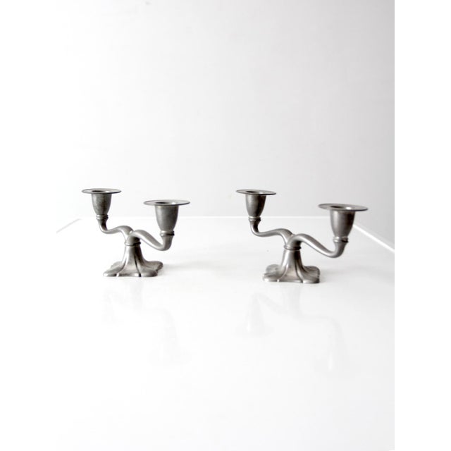 A graceful pair of early 20th-century Art Nouveau double candlesticks featuring flowing arms, flared candle cups, and...