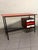 A fully restored 1960s writing desk. A sleek, black lacquered tubular iron frame with adjustable brass feet matches the...