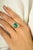 This dazzling ring showcases a vivid 3.56-carat emerald-cut emerald, beautifully framed by a delicate floral-inspired...