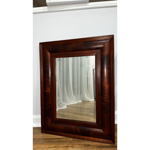 This striking 19th-century antique wall mirror features a classic Empire / Ogee mahogany veneer frame with rich grain and...