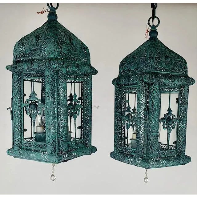 Elegant and full of character, this pair of hanging lanterns showcases intricate metal filigree design with a richly aged...
