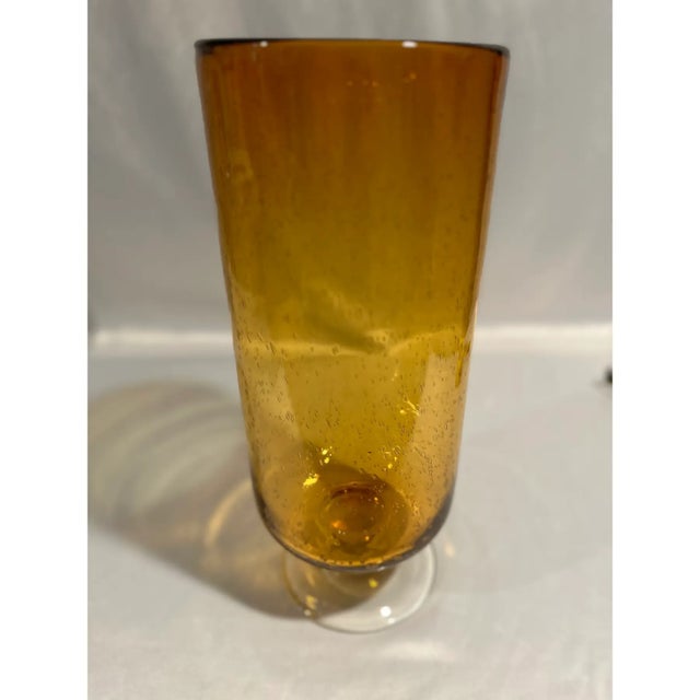 A large scale hand blown amber gold art glass footed vase with seeded bubbles throughout. The top of this heavy vase is an...