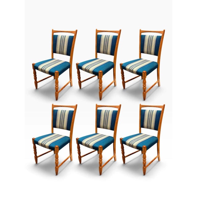 Here is a set of six Danish modern dining chairs designed by Henning Kjærnulf, with solid oak frames. Kjærnulf's sculpted...