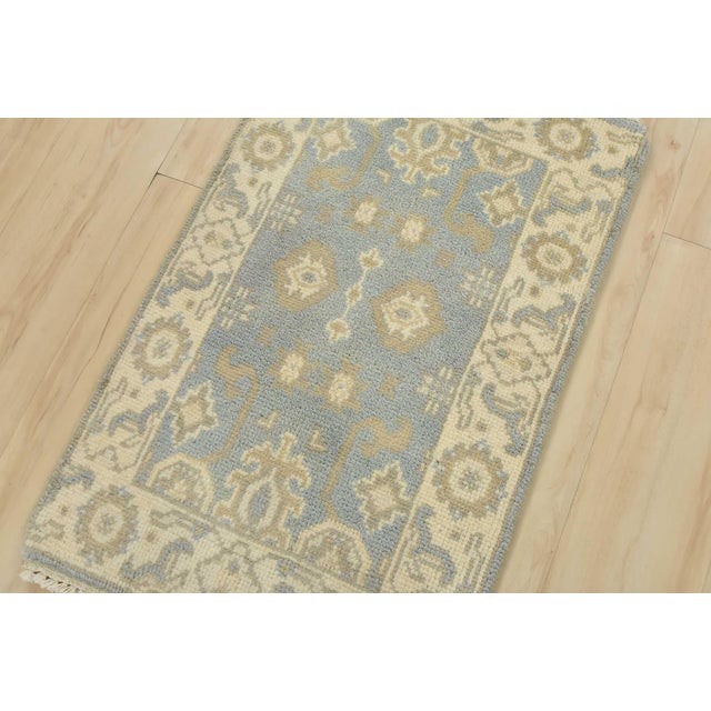 A traditional Oushak rug hand-knotted with an all-wool pile on a cotton foundation. This oriental rug features muted...
