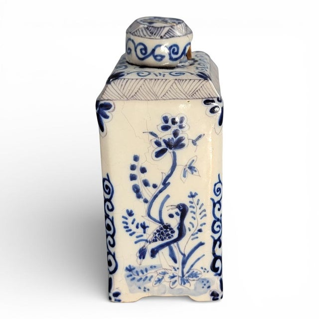 This antique Dutch Delftware tea caddy presents a classic blue-and-white palette, executed in underglaze cobalt on a tin-...