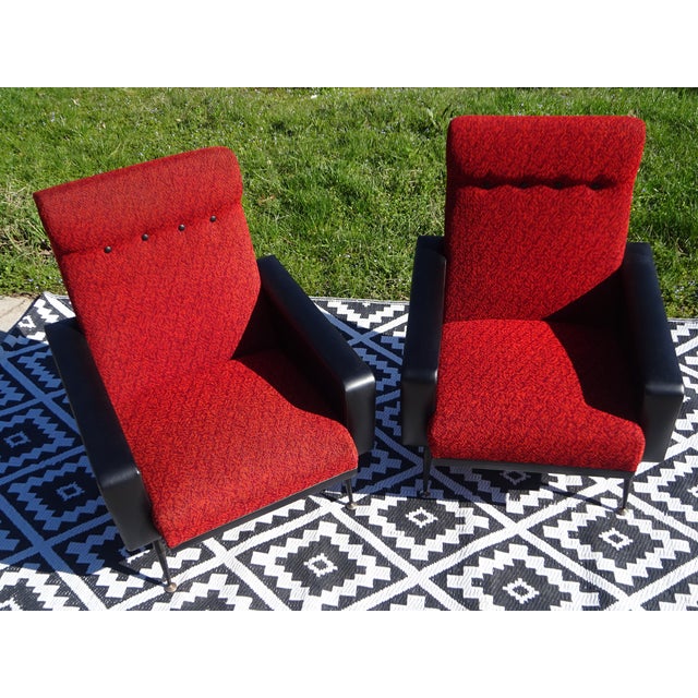 Red and black faux leather and fabric armchairs with splayed legs. Black faux leather armrests. Seat and back upholstered...