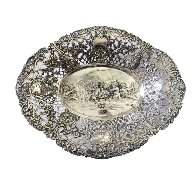 This exquisite oval bowl/basket, crafted in Germany around 1900, features intricate pierced walls adorned with repousse...