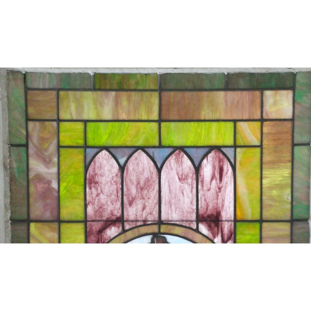 19th century stained glass church window with a wooden frame and center cross motif. There are hand painted details of an...