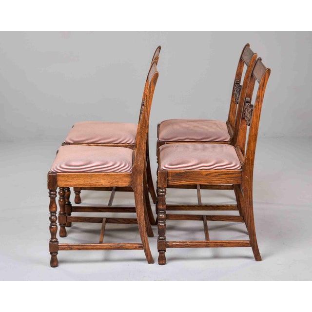 A set of four late Victorian oak side chairs, circa 1890, carrying the ornate confidence of the Gothic Revival style. The...