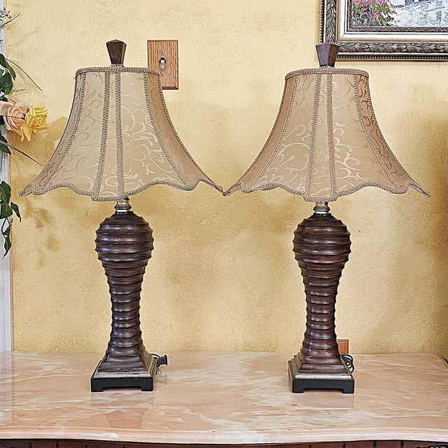 Handsome pair of vintage Uttermost urn-form table lamps with a richly textured, carved wood-look finish. Likely late...