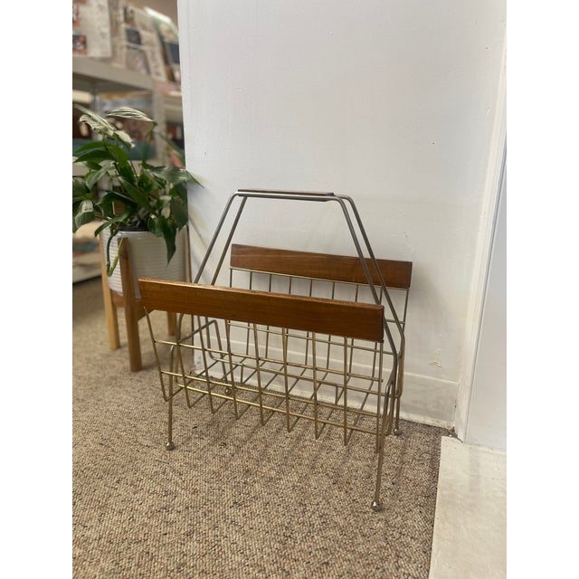 This vintage mid-century modern magazine rack combines clean lines with a warm material palette, showcasing hallmark...