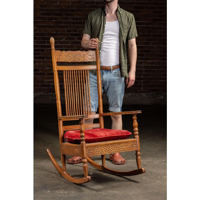 Antique oak spindle-back rocking chair with carved details. Featuring a tall spindle-back design, this piece offers...