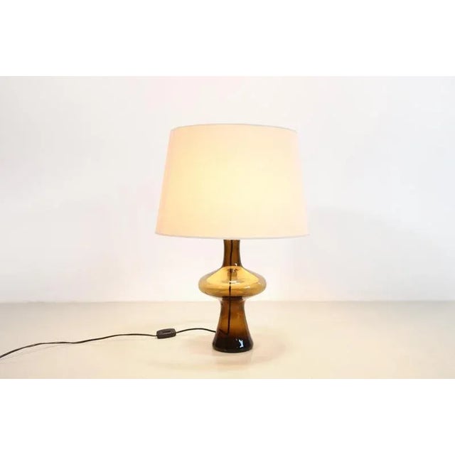 Beautiful table lamp by Lisbeth Brams for Fog and Morup from 1968. The amber-colored smoked glass base has a beautiful...