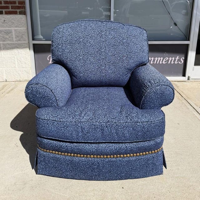 This custom upholstered blue club chair features a graceful back, rolled arms, and a richly textured patterned fabric that...