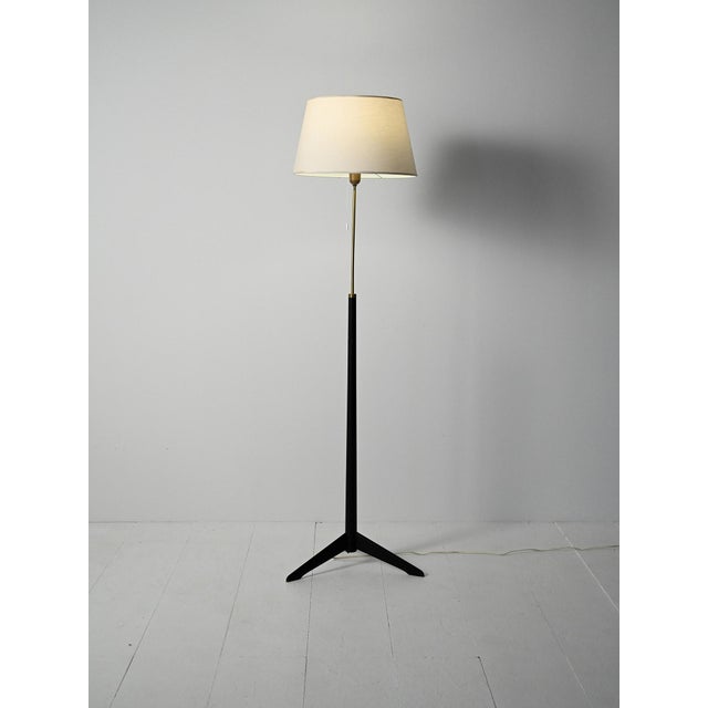 1950s/1960s floor lamp in black lacquered wood and brass, with a trilobed base. Lampshade remade in the style of the...