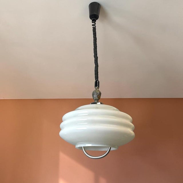 Elegant Mid-Century Modern hanging pendant lamp featuring a beautifully reverse-painted white glass shade with a soft...