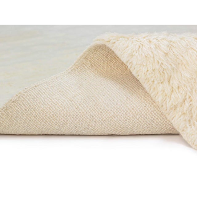 Minimalist hand-knotted Ivory wool rug, embodying a sense of subtle sophistication with its simple yet elegant design,...